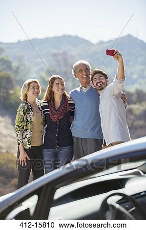 Family taking self-portrait with cell phone outside car View Large Photo Image Stock Image - Family taking self-portrait with cell phone outside car. Fotosearch