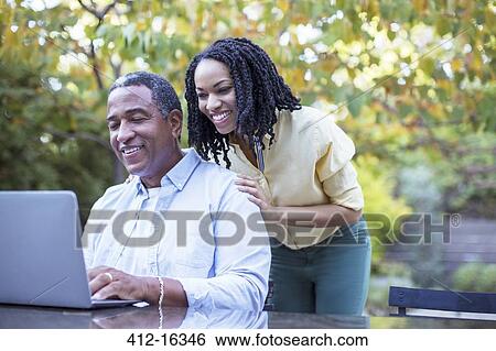 Father and daughter using laptop at patio table View Large Photo Image Stock Photograph - Father and daughter using laptop at patio table. Fotosearch