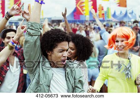 Stock Image - Friends dancing and cheering at music festival. Fotosearch