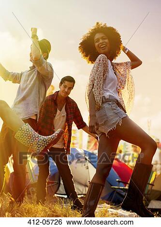 Stock Photograph - Friends dancing outside tents at music festival. Fotosearch