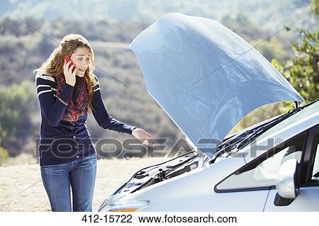 Frustrated woman talking on cell phone with automobile hood raised at roadside View Large Photo Image Stock Image - Frustrated woman talking on cell phone with automobile hood raised at roadside. Fotosearch