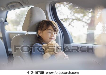 Stock Photo - Girl with teddy bear sleeping in back seat of car. Fotosearch