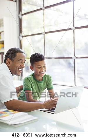Stock Image - Grandfather and grandson using laptop. Fotosearch