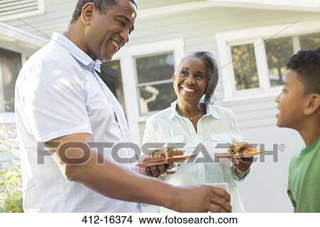 Picture - Grandparents and grandson enjoying barbecue on patio. Fotosearch