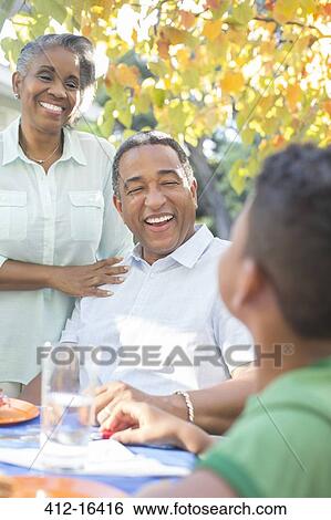 Grandparents and grandson laughing at patio table View Large Photo Image Stock Photograph - Grandparents and grandson laughing at patio table. Fotosearch