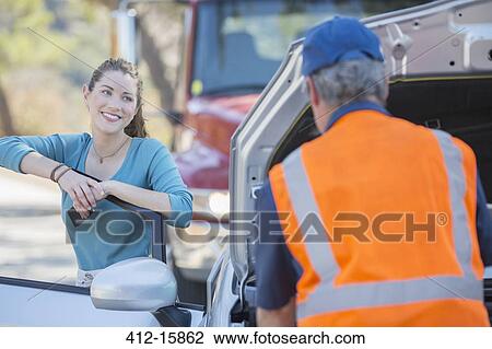 Grateful woman watching roadside mechanic fix car View Large Photo Image Stock Image - Grateful woman watching roadside mechanic fix car. Fotosearch