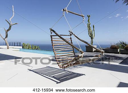 Hanging wooden chair on luxury patio overlooking ocean View Large Photo Image Picture - Hanging wooden chair on luxury patio overlooking ocean. Fotosearch