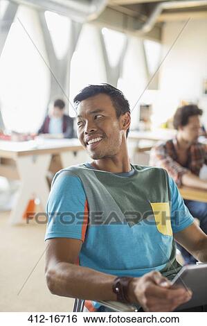Happy casual businessman looking over shoulder in office View Large Photo Image Stock Photograph - Happy casual businessman looking over shoulder in office. Fotosearch