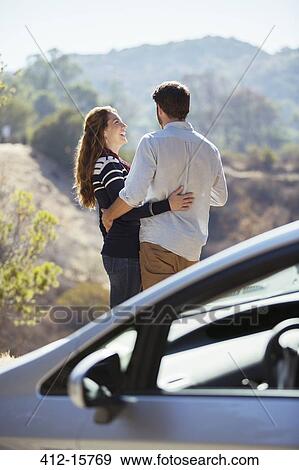 Happy couple hugging at roadside outside car View Large Photo Image Stock Photo - Happy couple hugging at roadside outside car. Fotosearch