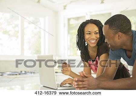 Happy couple shopping online at laptop in kitchen View Large Photo Image Stock Photo - Happy couple shopping online at laptop in kitchen. Fotosearch