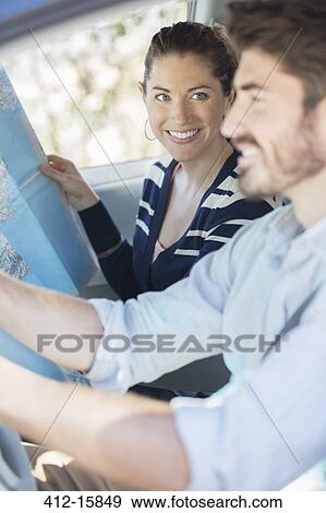 Stock Photo - Happy couple with map inside car. Fotosearch