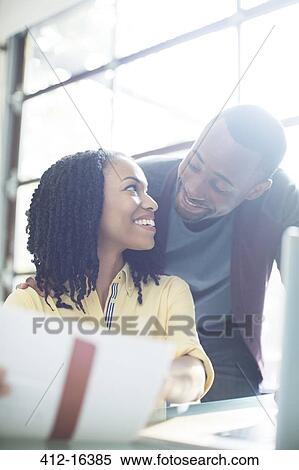 Stock Photography - Happy couple with paperwork at laptop. Fotosearch