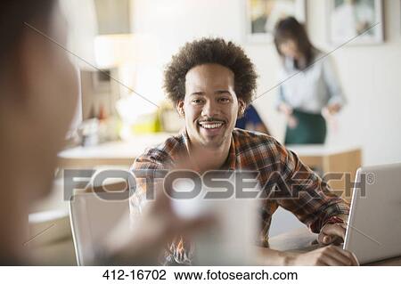 Stock Image - Happy creative businessman using laptop in meeting. Fotosearch