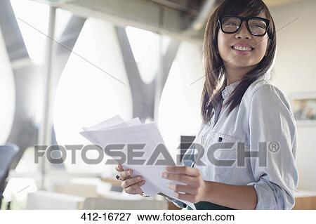 Happy creative businesswoman with paperwork in office View Large Photo Image Stock Photo - Happy creative businesswoman with paperwork in office. Fotosearch