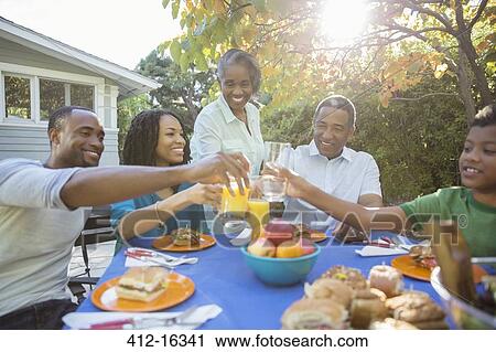 Happy family toasting juice glasses at patio table View Large Photo Image Stock Image - Happy family toasting juice glasses at patio table. Fotosearch