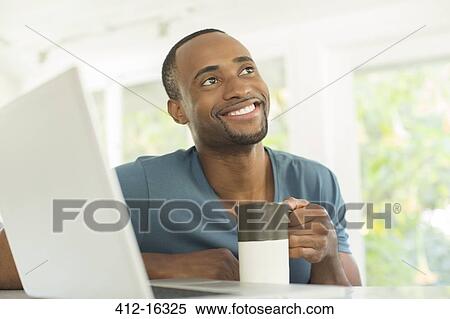 Happy man drinking coffee at laptop View Large Photo Image Stock Photography - Happy man drinking coffee at laptop. Fotosearch