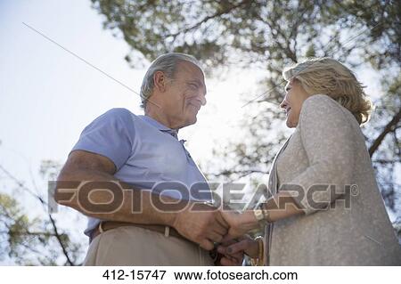 Happy senior couple holding hands under tree View Large Photo Image Stock Photo - Happy senior couple holding hands under tree. Fotosearch