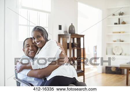 Happy senior couple hugging in living room View Large Photo Image Stock Photography - Happy senior couple hugging in living room. Fotosearch