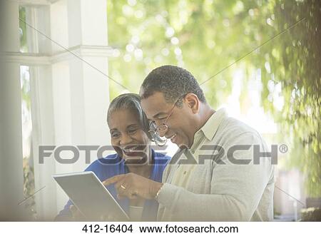Happy senior couple using digital tablet on porch View Large Photo Image Picture - Happy senior couple using digital tablet on porch. Fotosearch