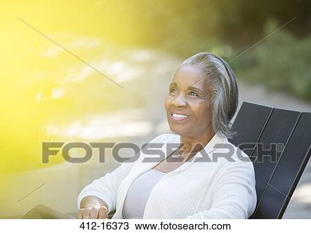 Happy senior woman sitting on patio View Large Photo Image Stock Image - Happy senior woman sitting on patio. Fotosearch