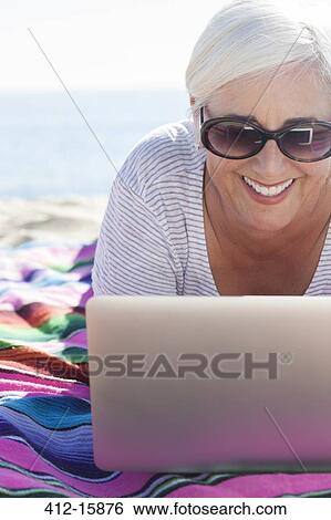 Happy woman using laptop on beach View Large Photo Image Stock Photograph - Happy woman using laptop on beach. Fotosearch