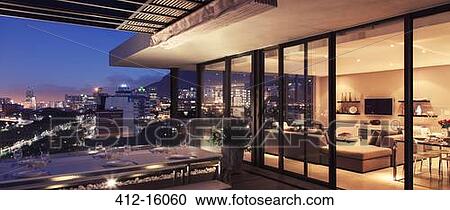 Illuminated modern living room and patio overlooking city View Large Photo Image Stock Image - Illuminated modern living room and patio overlooking city. Fotosearch