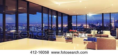 Illuminated modern living room overlooking city View Large Photo Image Stock Photo - Illuminated modern living room overlooking city. Fotosearch