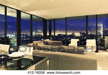Stock Photograph - Illuminated modern living room overlooking city. Fotosearch