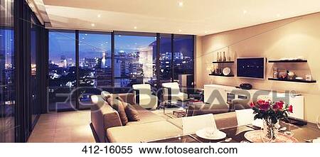 Stock Photography - Illuminated modern living room overlooking city. Fotosearch