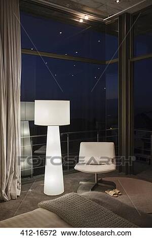 Stock Image - Lamp and chair in corner of modern bedroom. Fotosearch