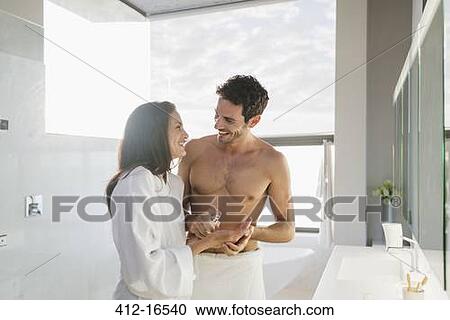 Stock Image - Man dispensing moisturizer in woman's hand. Fotosearch