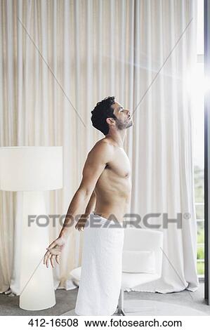 Man in towel basking in sunlight at bedroom window View Large Photo Image Stock Photo - Man in towel basking in sunlight at bedroom window. Fotosearch