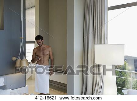 Man in towel texting with cell phone in bedroom View Large Photo Image Stock Image - Man in towel texting with cell phone in bedroom. Fotosearch