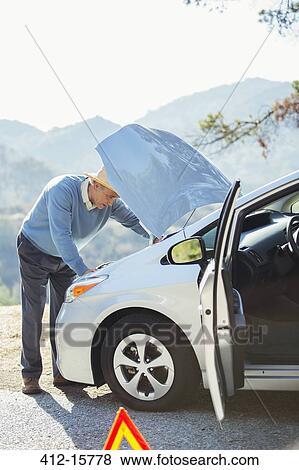 Man looking at car engine at roadside View Large Photo Image Stock Photo - Man looking at car engine at roadside. Fotosearch
