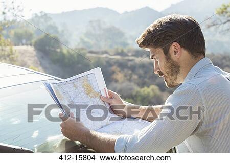 Picture - Man looking at map outside car. Fotosearch