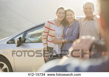 Man photographing family outside car View Large Photo Image Picture - Man photographing family outside car. Fotosearch