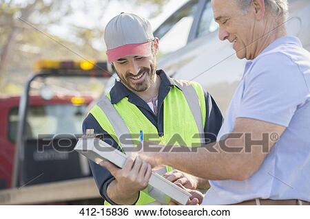 Man signing paperwork for roadside mechanic View Large Photo Image Stock Photograph - Man signing paperwork for roadside mechanic. Fotosearch