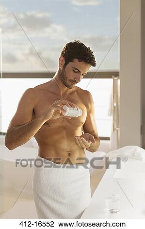 Stock Image - Man taking medication in bathroom. Fotosearch