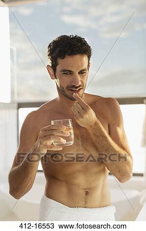 Man taking medication with water in bathroom View Large Photo Image Stock Image - Man taking medication with water in bathroom. Fotosearch