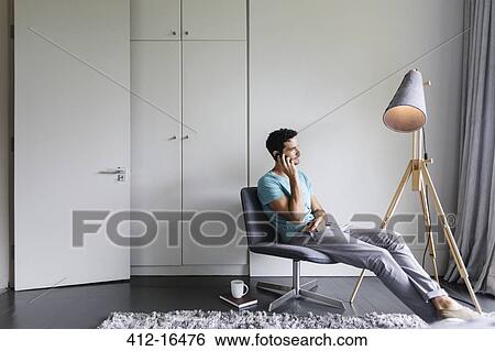 Man talking on cell phone in living room View Large Photo Image Stock Photograph - Man talking on cell phone in living room. Fotosearch