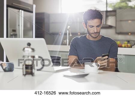 Man texting with cell phone at kitchen table View Large Photo Image Stock Photograph - Man texting with cell phone at kitchen table. Fotosearch