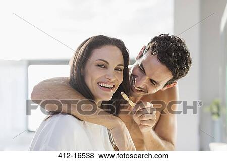 Stock Photo - Man trying to brush woman's teeth in bathroom. Fotosearch