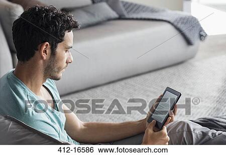 Stock Photograph - Man using digital tablet in bedroom. Fotosearch