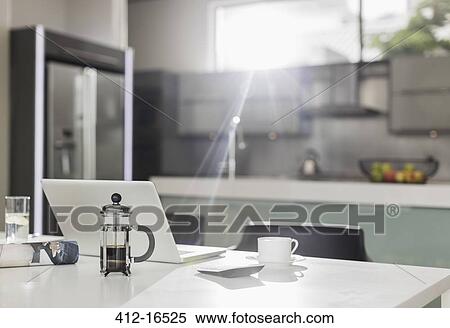 Stock Photography - Morning sun shining on laptop in kitchen. Fotosearch
