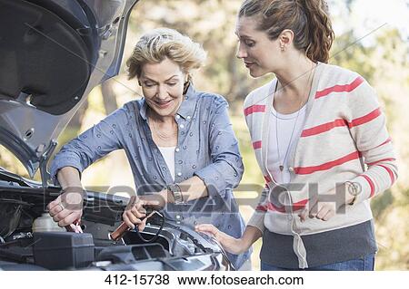 Stock Photo - Mother and daughter jump starting car. Fotosearch