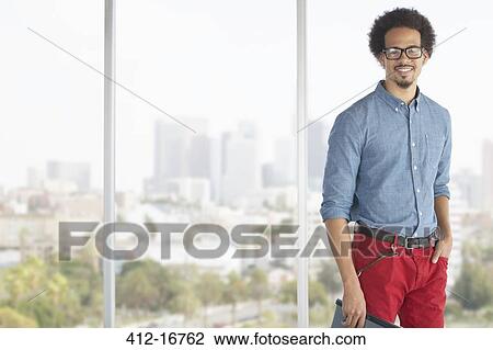 Portrait of casual businessman at window overlooking city View Large Photo Image Stock Image - Portrait of casual businessman at window overlooking city. Fotosearch