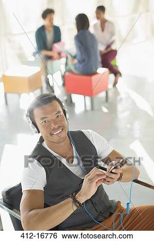 Portrait of casual businessman listening to music on headphones with mp3 player View Large Photo Image Stock Photograph - Portrait of casual businessman listening to music on headphones with mp3 player. Fotosearch
