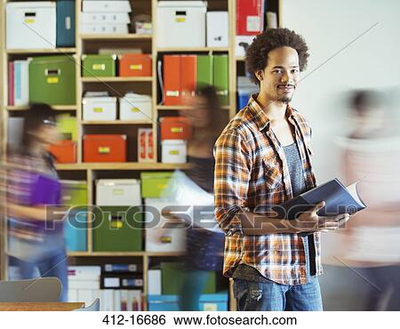 Portrait of casual businessman with co-workers rushing by in background View Large Photo Image Stock Photograph - Portrait of casual businessman with co-workers rushing by in background. Fotosearch