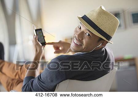 Portrait of confident man in fedora listening to music on headphones with mp3 player View Large Photo Image Stock Photo - Portrait of confident man in fedora listening to music on headphones with mp3 player. Fotosearch