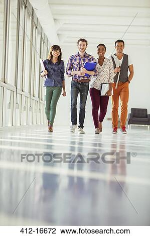 Portrait of creative business people walking in sunny corridor View Large Photo Image Stock Image - Portrait of creative business people walking in sunny corridor. Fotosearch